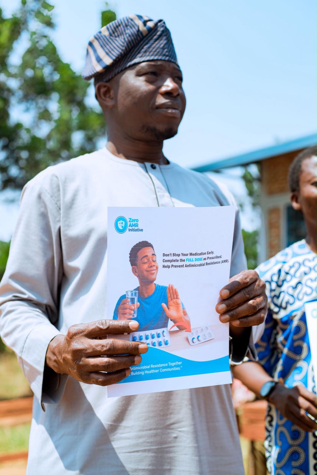 A portrait of a young participant holding a Zero AMR Initiative information leaflet